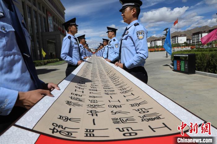 图为日喀则边境管理支队机关民警一齐展示百米长卷。　西藏出入境边防检查总站供图